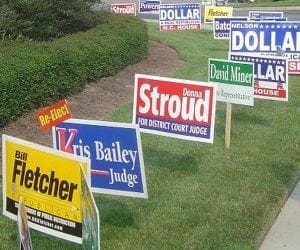 yard signs staggered in a yard with various colors and slogans